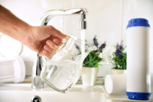Person filling glass pitcher from Water Filtration System